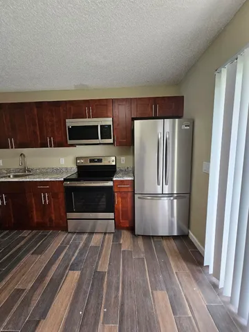 a kitchen with granite countertop a refrigerator and a stove top oven