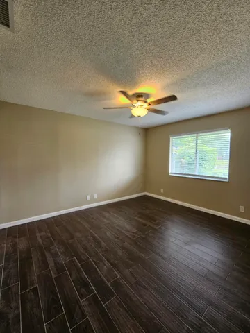 an empty room with wooden floor cabinets and windows