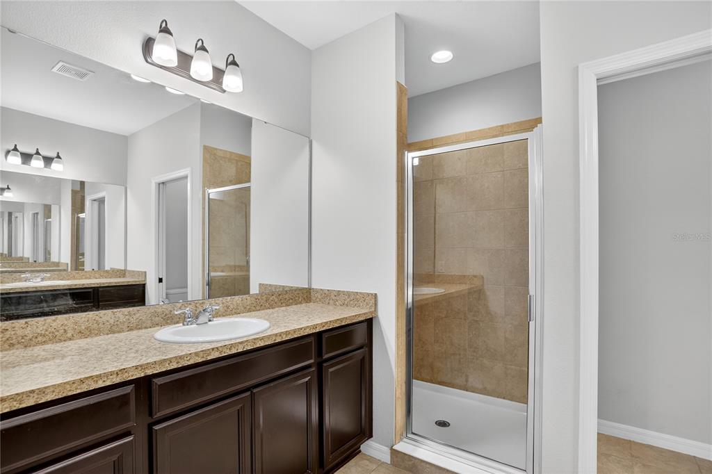 613 Fortanini Circle Ocoee, FL 34761 - Photo 13 of 24 a bathroom with a granite countertop sink a mirror and a shower
