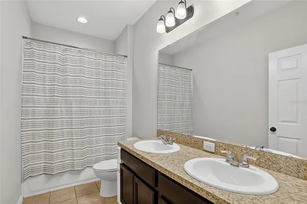 a bathroom with a granite countertop sink toilet a mirror and shower curtain
