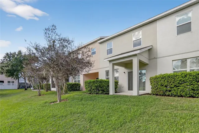a view of a white house next to a yard with big trees
