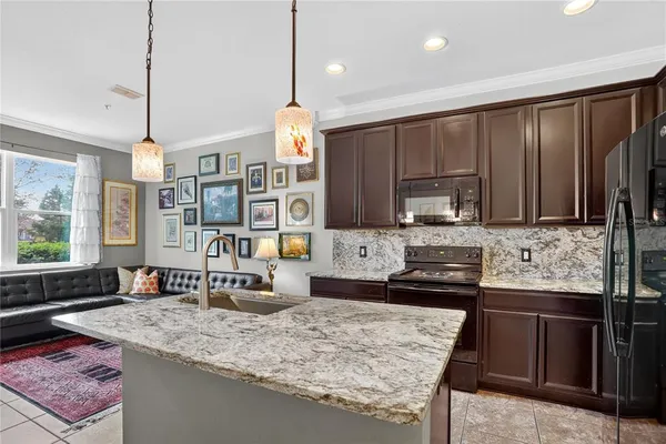 a kitchen with kitchen island granite countertop a sink stove and wooden cabinets