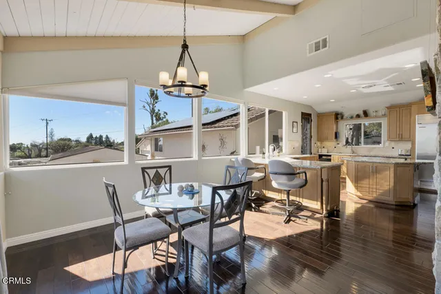 a dining room with wooden floor a chandelier a glass table and chairs