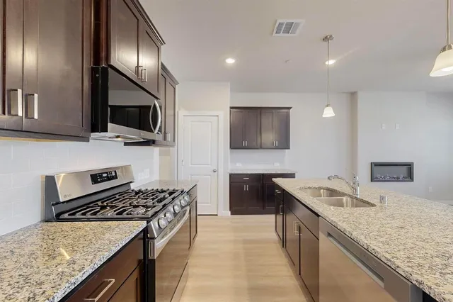 a view of kitchen with granite countertop stainless steel appliances refrigerator sink and stove