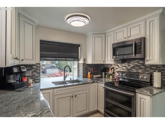 a kitchen with stainless steel appliances granite countertop a sink stove and microwave