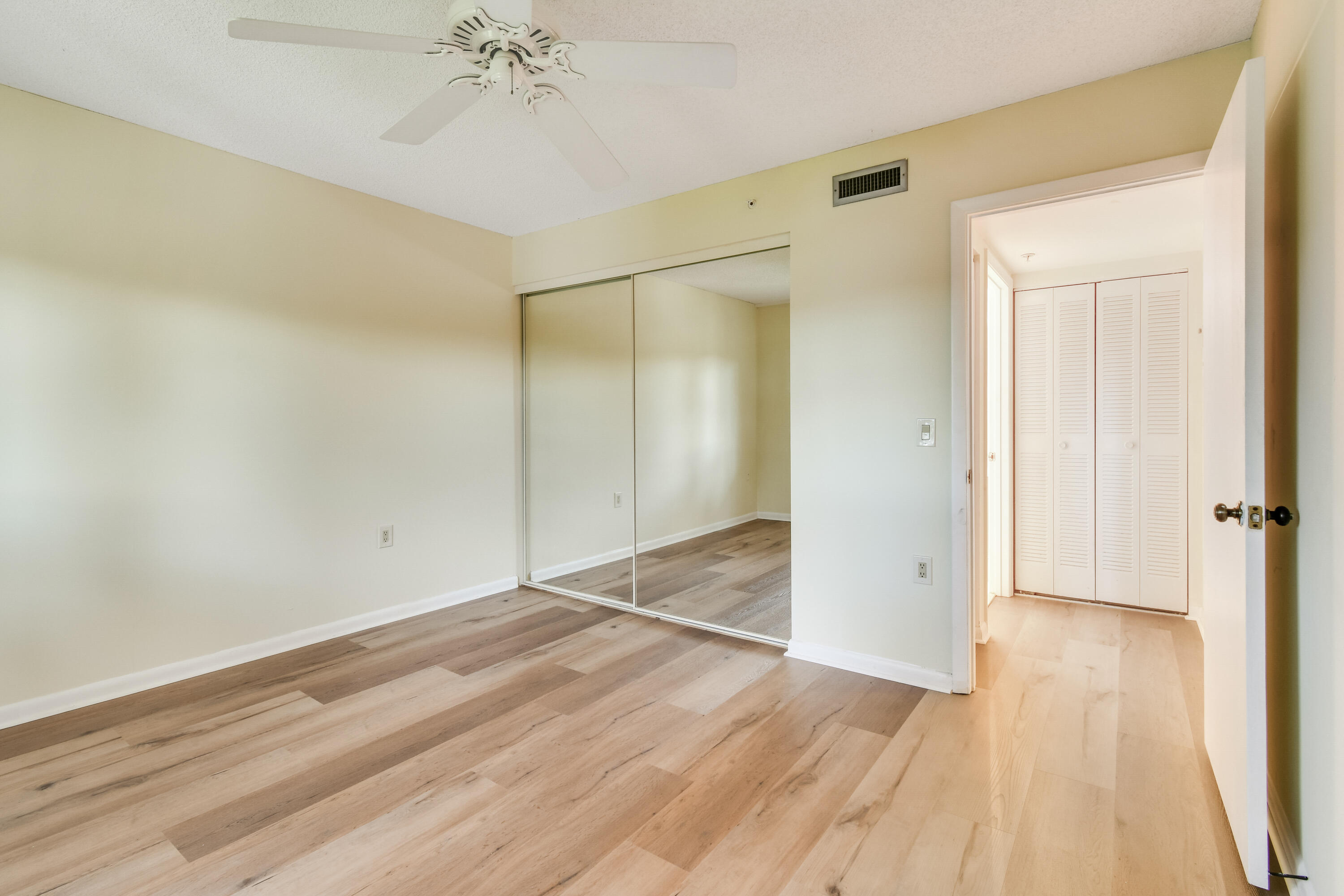 1701 Marina Isle Way, Unit 301 Jupiter, FL 33477 - Photo 36 of 60 an empty room with wooden floor and a ceiling fan