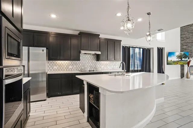 a large white kitchen with a stove a sink dishwasher and a refrigerator with wooden floor