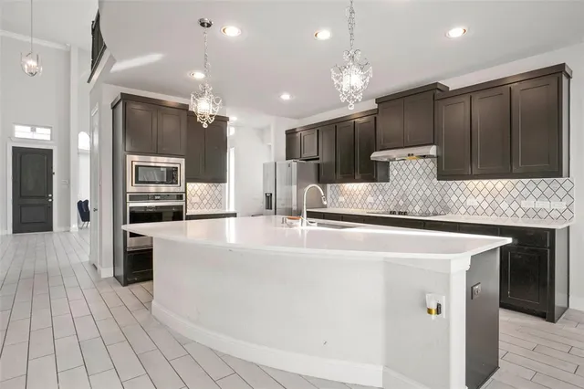 a large white kitchen with kitchen island a sink stainless steel appliances and cabinets