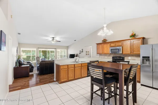 a kitchen with stainless steel appliances granite countertop a stove top oven a sink dishwasher a dining table and chairs with wooden floor