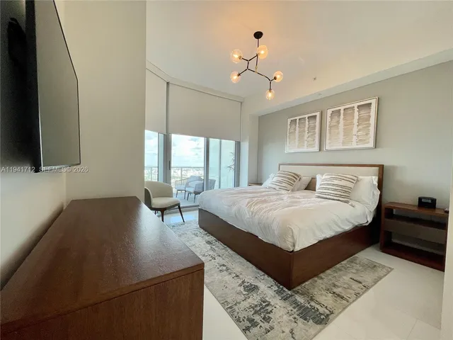 a spacious bedroom with a large bed and a chandelier