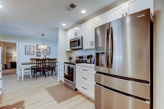 a dining room with wooden floor a chandelier a wooden table and chairs