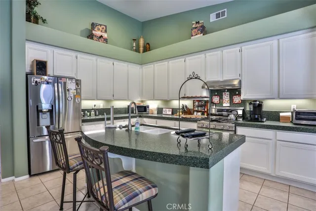 a kitchen with granite countertop a table chairs microwave and refrigerator