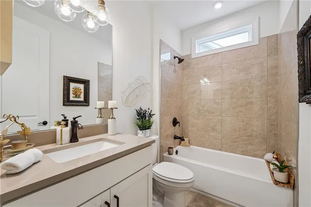 a bathroom with a granite countertop sink a toilet a mirror a bathtub and shower