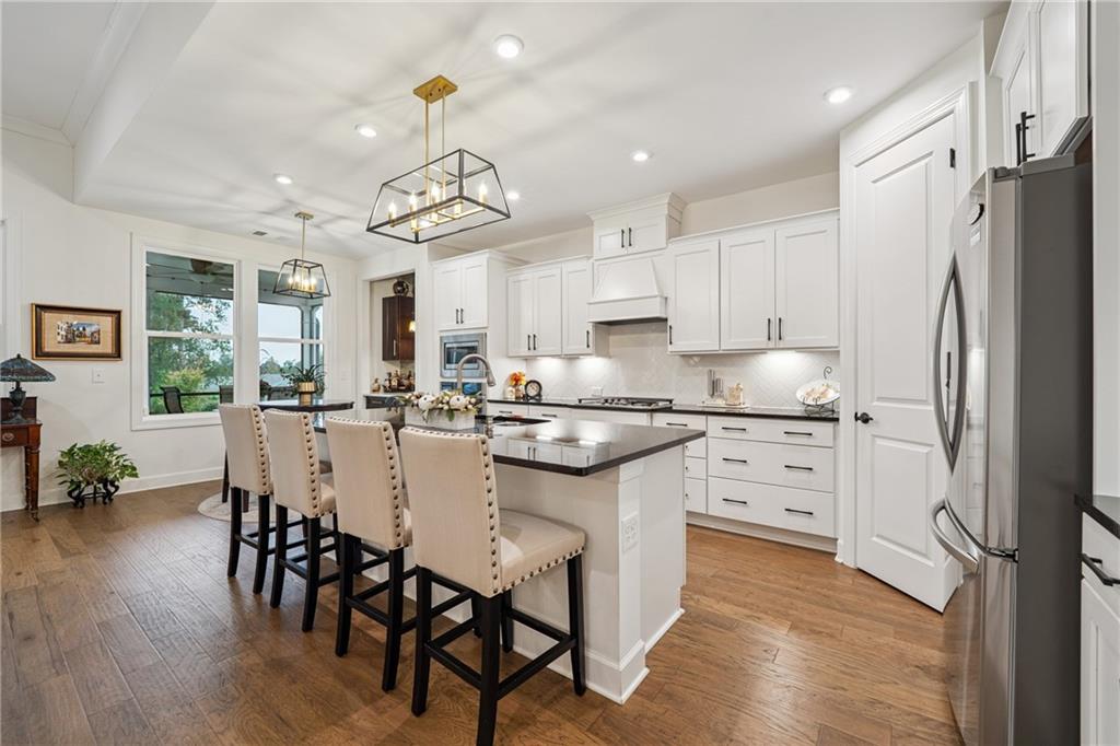 103 Rabun Court Hoschton, GA 30548 - Photo 7 of 22 a kitchen with kitchen island granite countertop a center island a refrigerator and a dining table