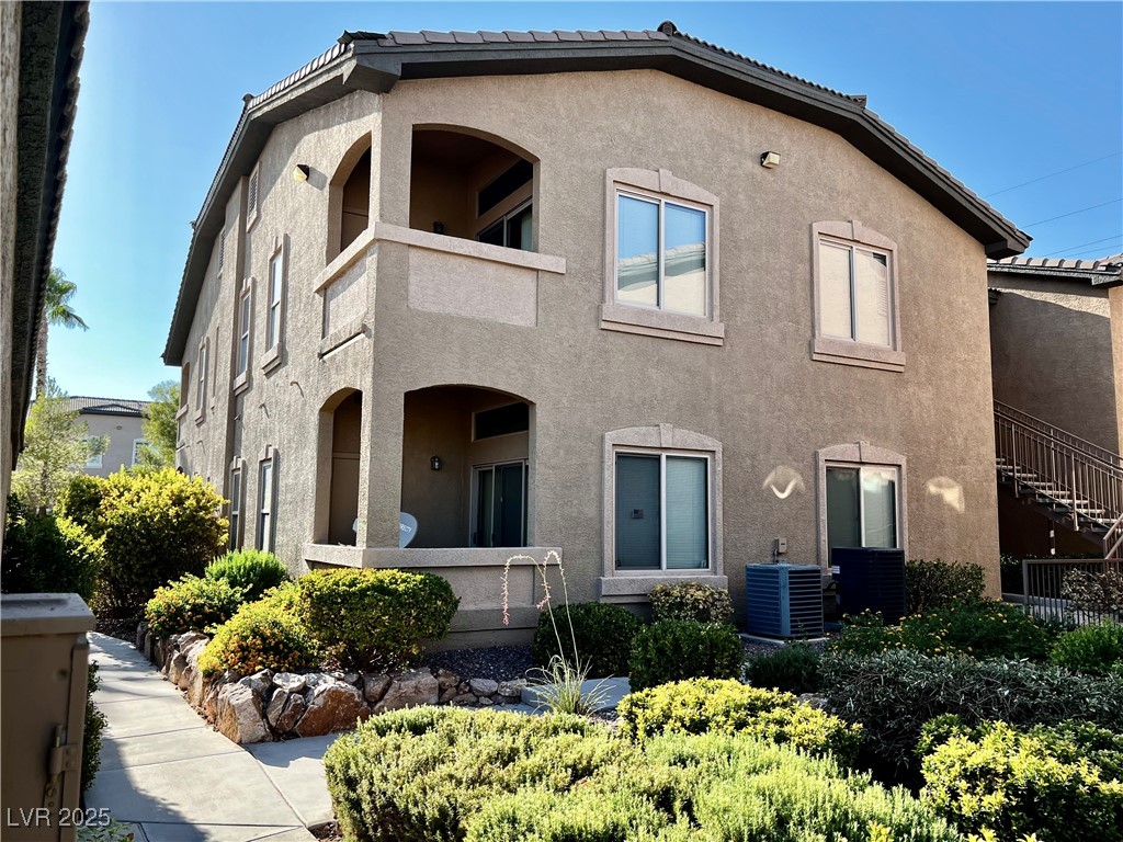 Rear view of house featuring stucco siding, a balcony, and a tile roof
