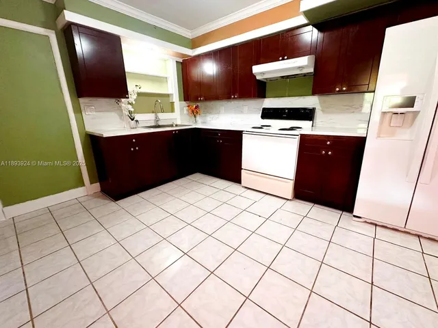 a kitchen with stainless steel appliances a sink a stove a refrigerator a microwave a sink and white cabinets