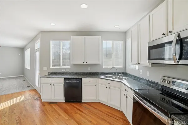 a kitchen with white cabinets appliances and wooden floor