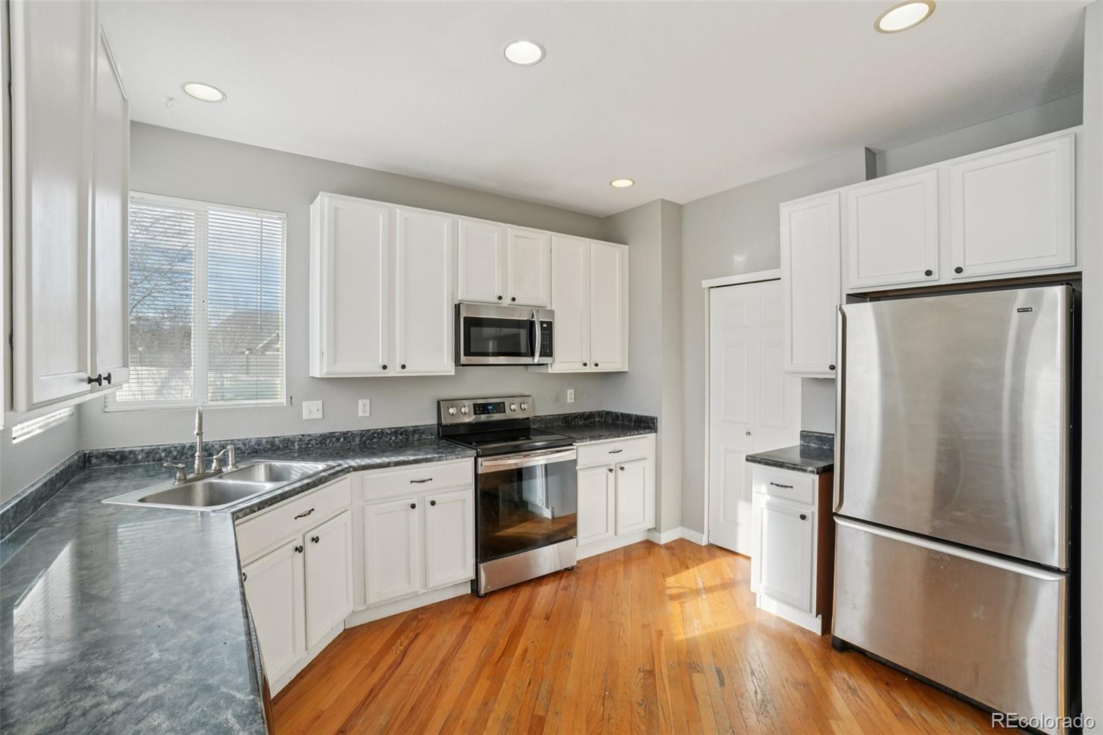 11205 Coal Ridge Street Firestone, CO 80504 - Photo 12 of 40 a kitchen with white cabinets appliances and wooden floor