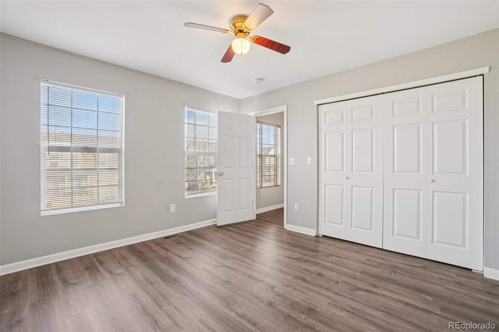 11205 Coal Ridge Street Firestone, CO 80504 - Photo 15 of 40 an empty room with wooden floor ceiling fan and windows