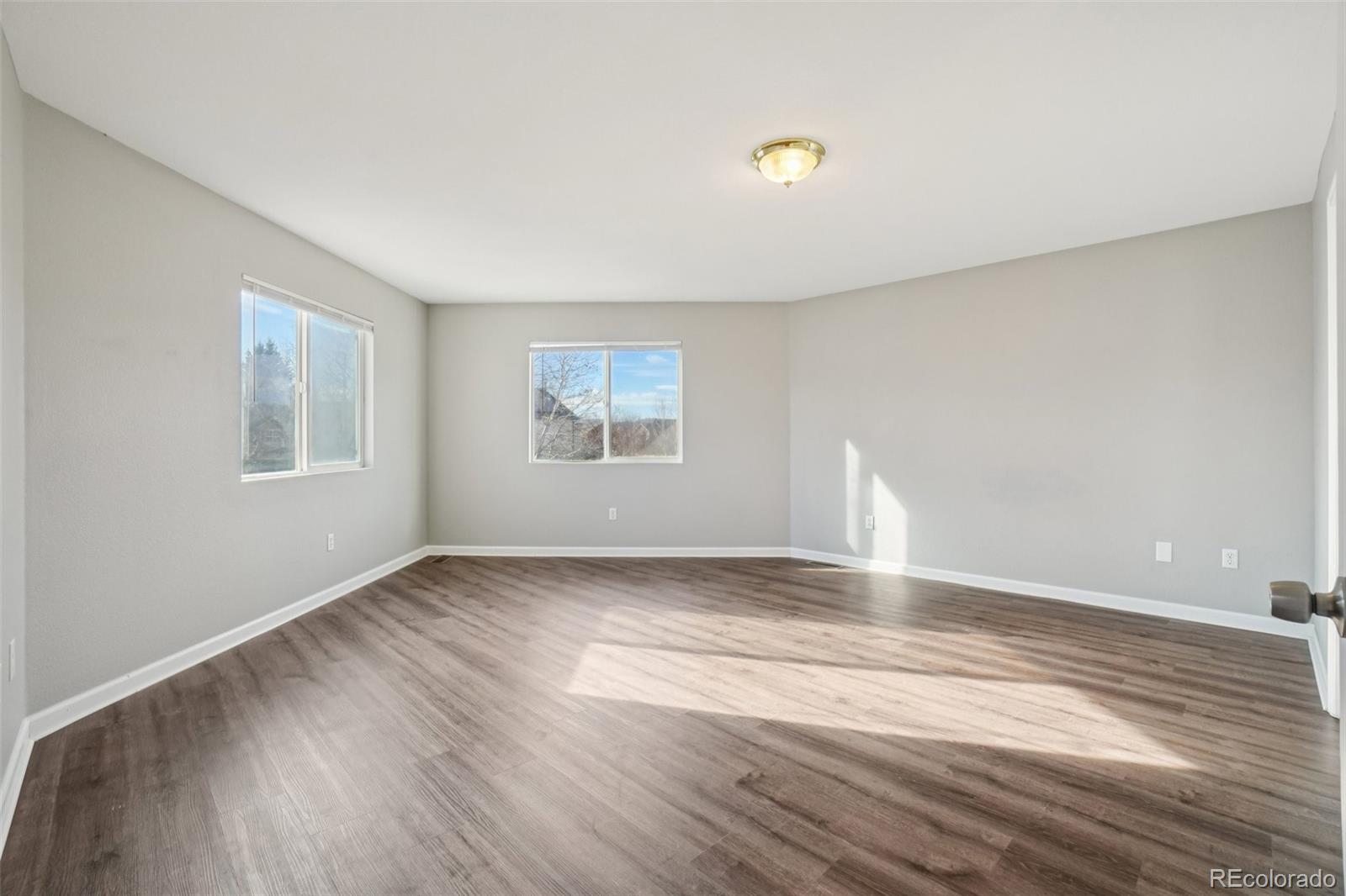 11205 Coal Ridge Street Firestone, CO 80504 - Photo 21 of 40 a view of an empty room with wooden floor and a window
