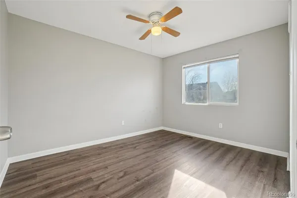 an empty room with wooden floor fan and windows
