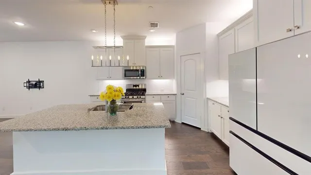 a kitchen with stainless steel appliances granite countertop a sink a refrigerator a stove and white cabinets