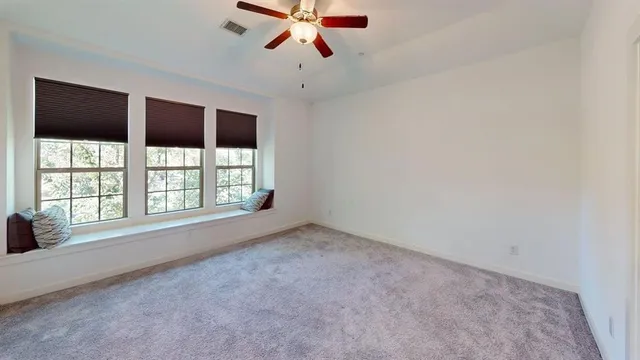 an empty room with windows and ceiling fan