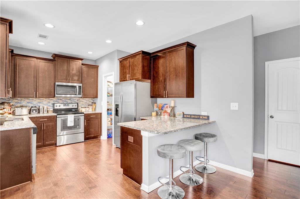 7789 Village Pass Fairburn, GA 30213 - Photo 19 of 35 a kitchen with granite countertop a sink appliances cabinets and wooden floor