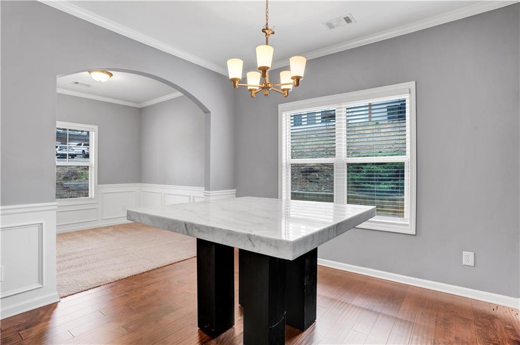 7789 Village Pass Fairburn, GA 30213 - Photo 8 of 35 a dining room with wooden floor a chandelier a wooden table and chairs