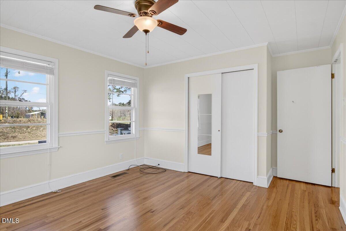 2118 Nutbush Road Henderson, NC 27537 - Photo 17 of 61 an empty room with wooden floor chandelier fan and windows