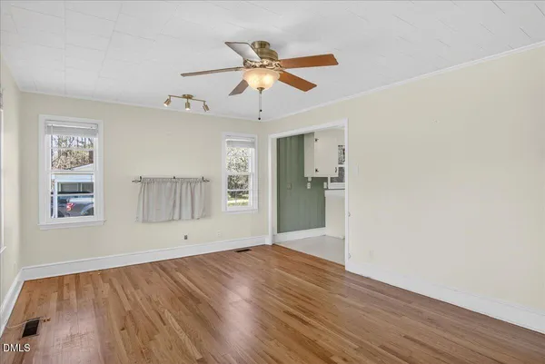 a view of an empty room with wooden floor and a window