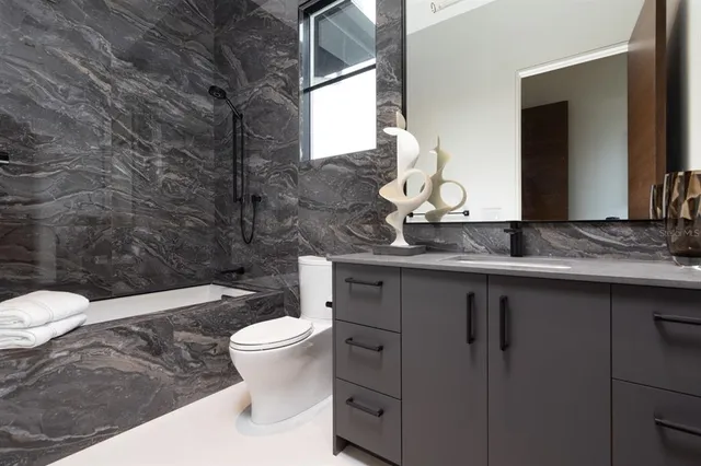 a bathroom with a granite countertop toilet sink and mirror