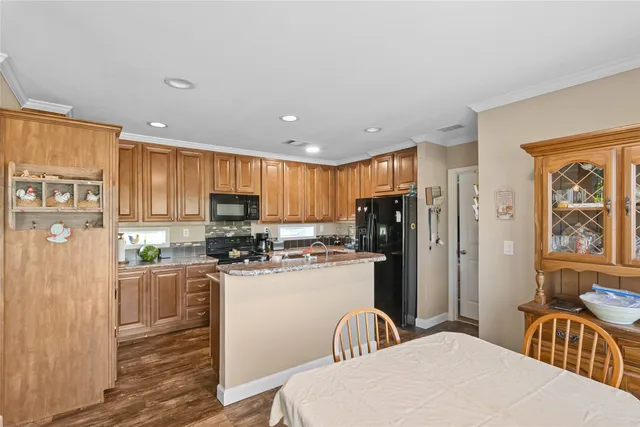 a kitchen with stainless steel appliances a sink a stove a refrigerator cabinets a dining table and chairs