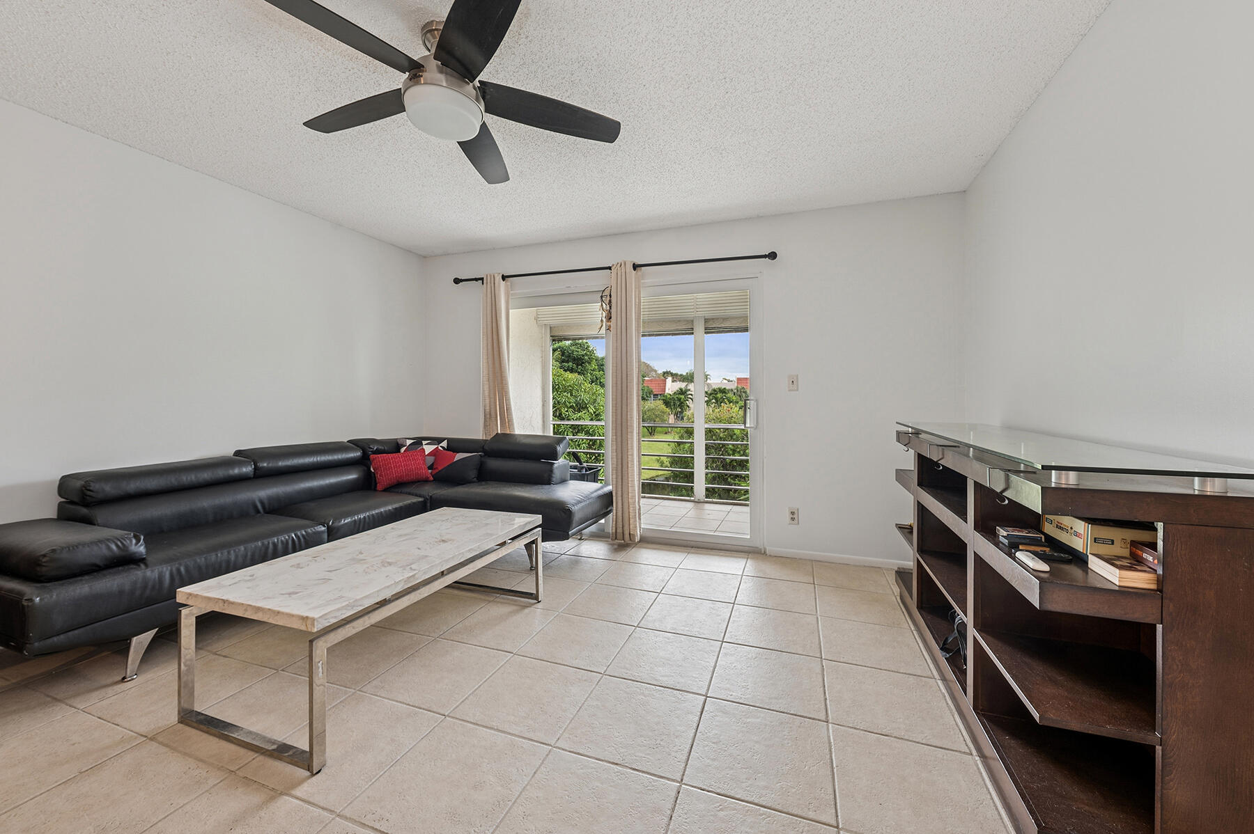 2700 Fiore Way, Unit 211 Delray Beach, FL 33445 - Photo 4 of 11 a living room with a couch and a ceiling fan