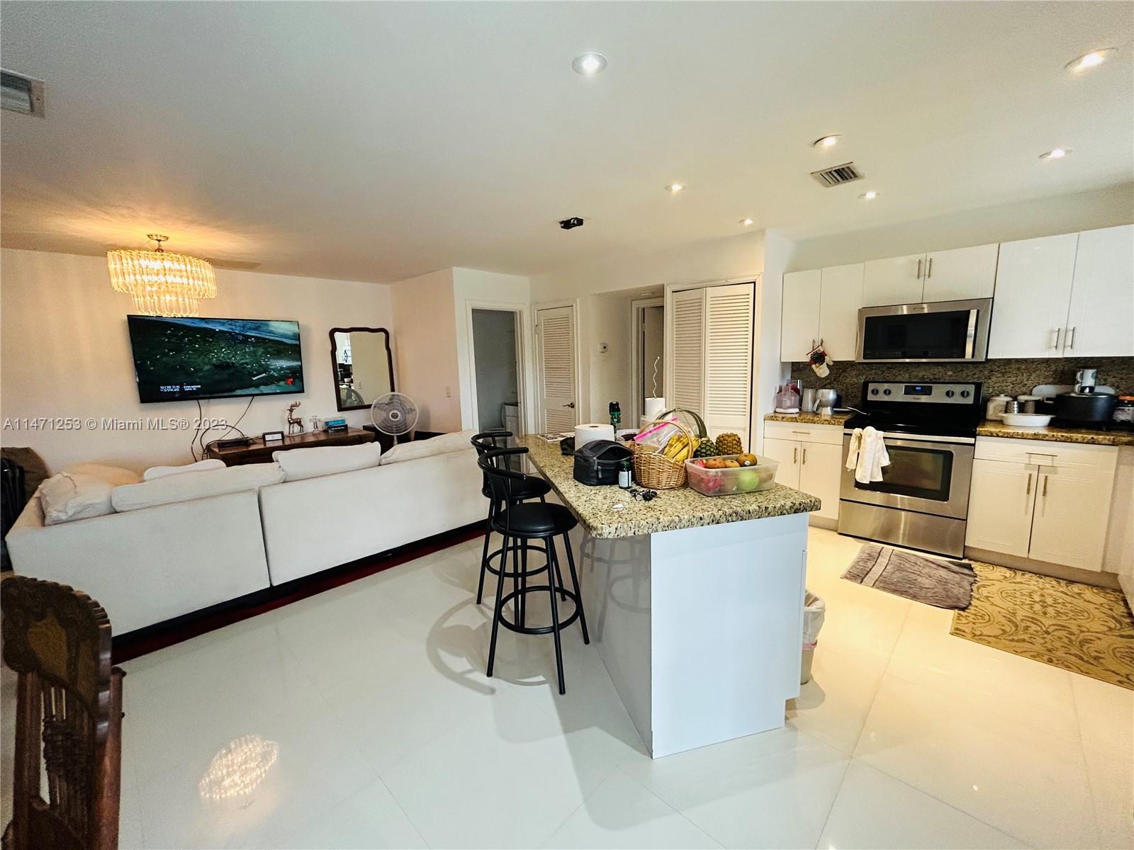 22795 Southwest 66th Avenue, Unit 205 Boca Raton, FL 33428 - Photo 3 of 33 a living room with stainless steel appliances furniture a flat screen tv and a kitchen view