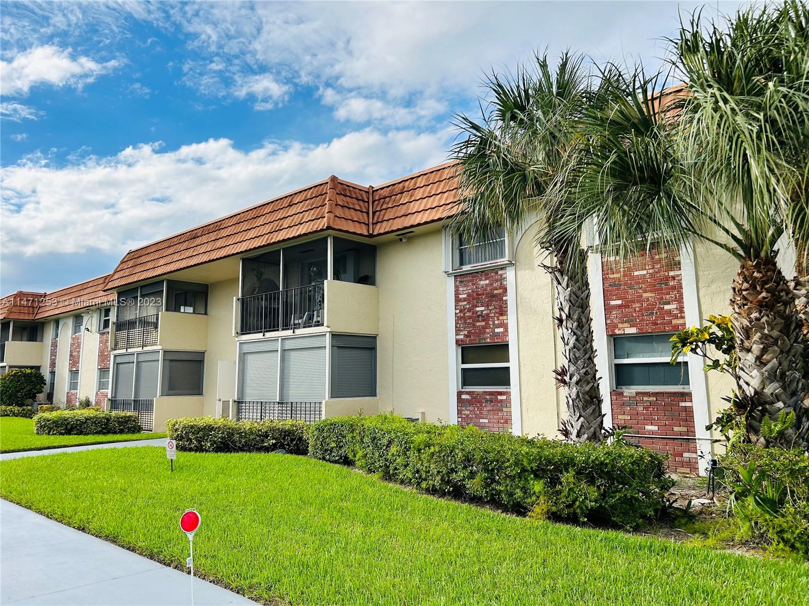 22795 Southwest 66th Avenue, Unit 205 Boca Raton, FL 33428 - Photo 32 of 33 a front view of a house with a garden and plants