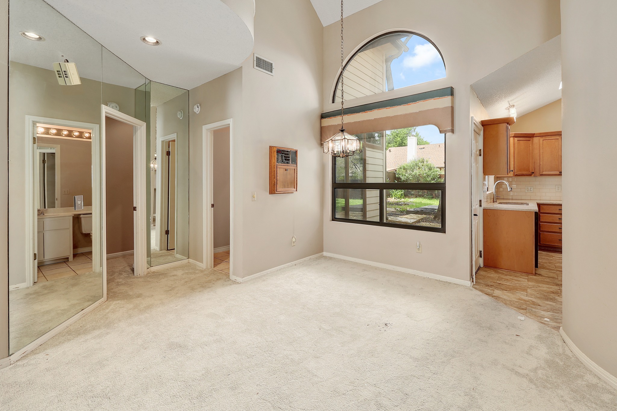 2202 Warfield Way Austin, TX 78728 - Photo 6 of 32 A well-lit interior space with a vaulted ceiling and a large arched window framing the outdoor greenery.