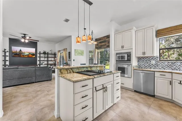 a kitchen with stainless steel appliances kitchen island granite countertop a stove a sink and a refrigerator