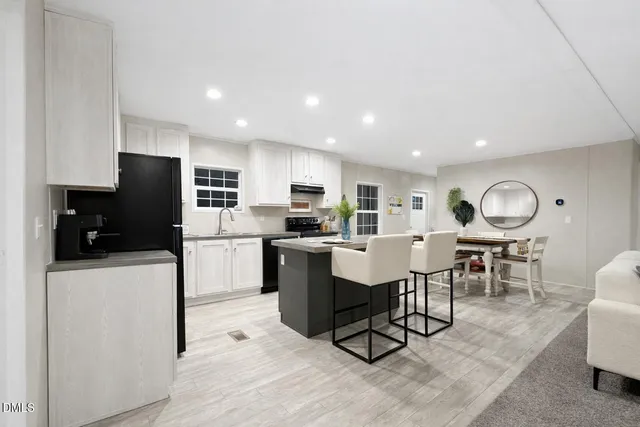 a living room with stainless steel appliances furniture a dining table and kitchen view