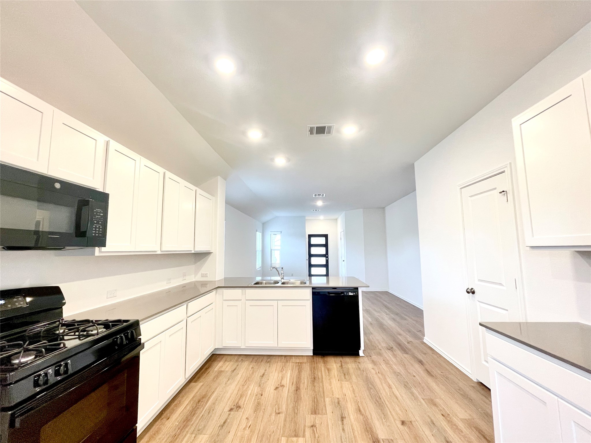 305 Milliner Loop Hutto, TX 78634 - Photo 17 of 36 a large kitchen with stainless steel appliances kitchen island granite countertop a stove a sink dishwasher and a microwave with wooden floor
