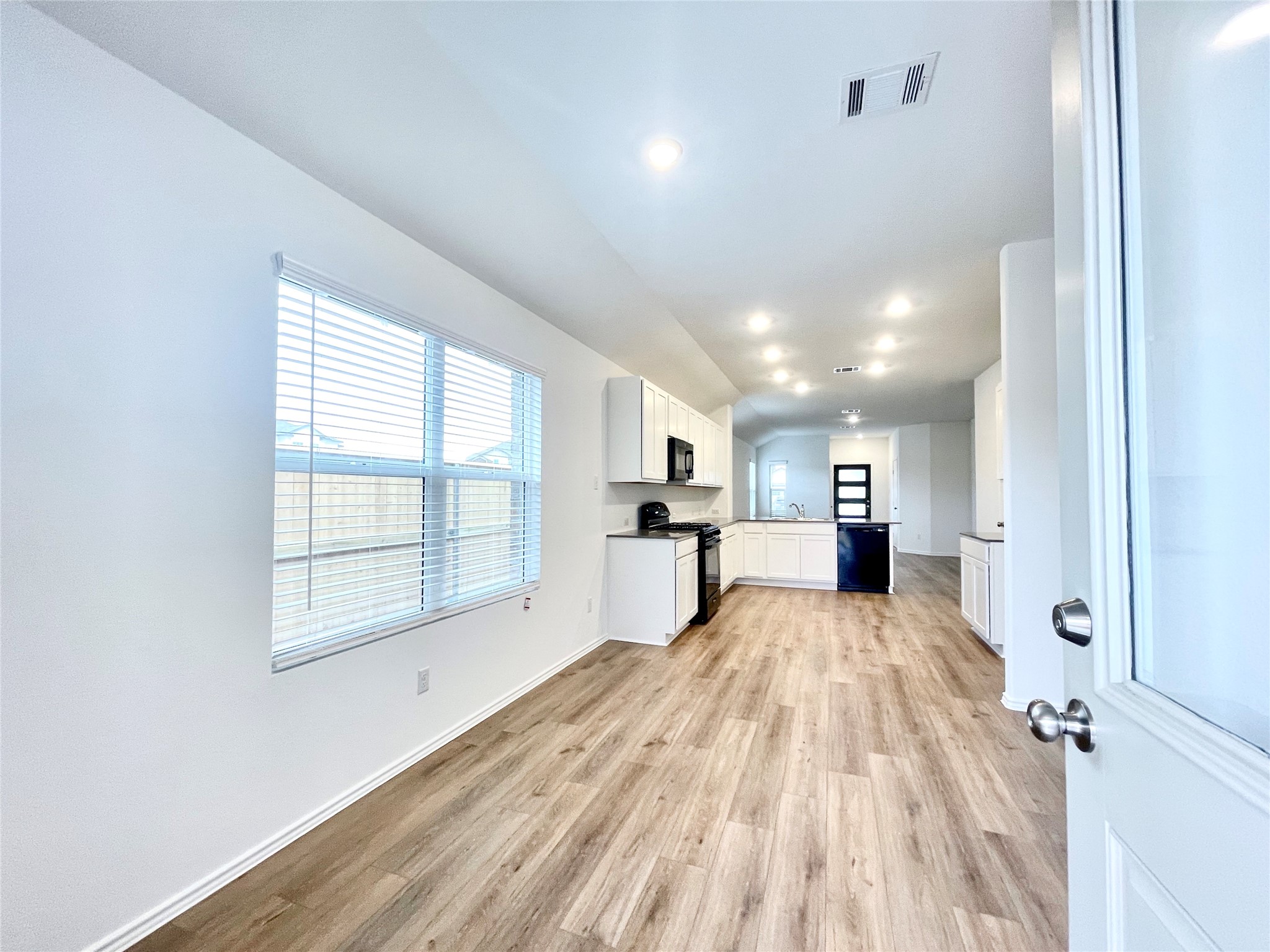 305 Milliner Loop Hutto, TX 78634 - Photo 10 of 36 an empty room with wooden floor kitchen view and windows