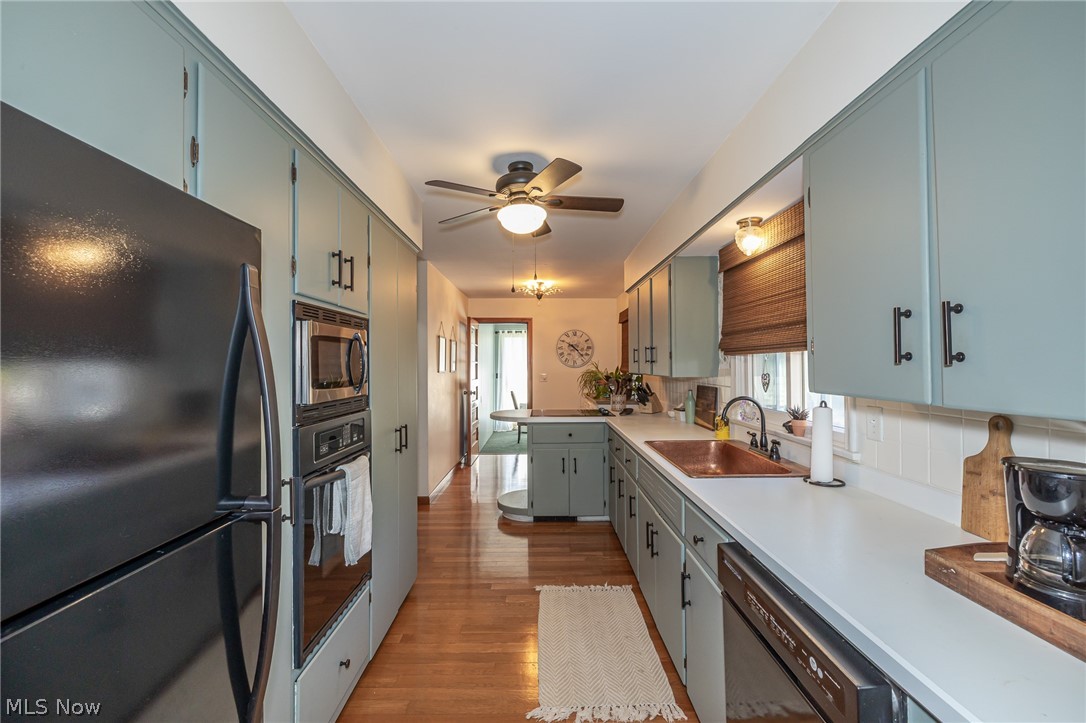 180 South Leavitt Road Amherst, OH 44001 - Photo 10 of 37 Kitchen featuring black appliances, light countertops, dark wood-style floors, backsplash, and ceiling fan