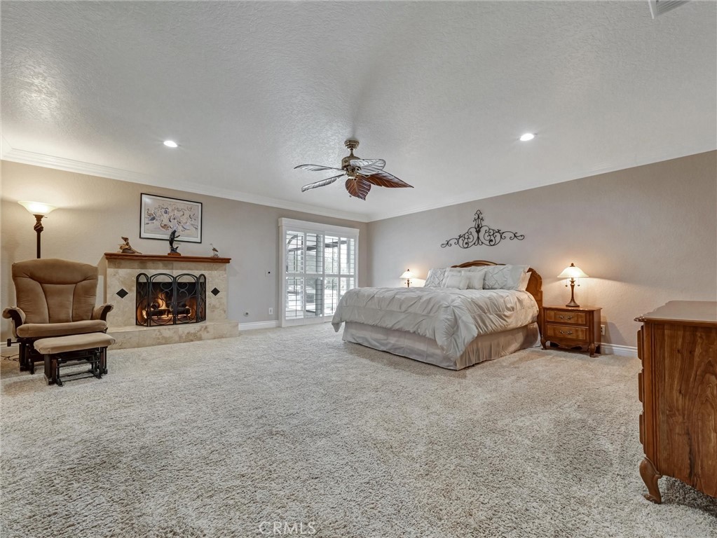 5831 Moonstone Avenue Rancho Cucamonga, CA 91701 - Photo 30 of 61 a spacious bedroom with a bed a fireplace and a chandelier