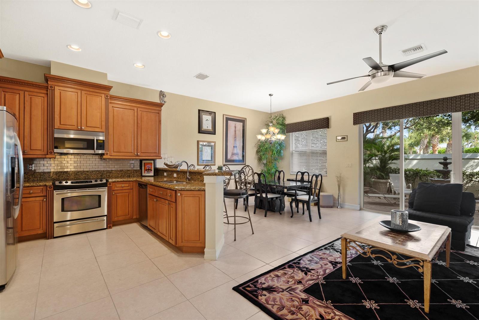 1000 North Us Highway, Unit 809 Jupiter, FL 33477 - Photo 7 of 30 a kitchen with stainless steel appliances granite countertop a stove top oven a sink a dining table and chairs with the view of living room