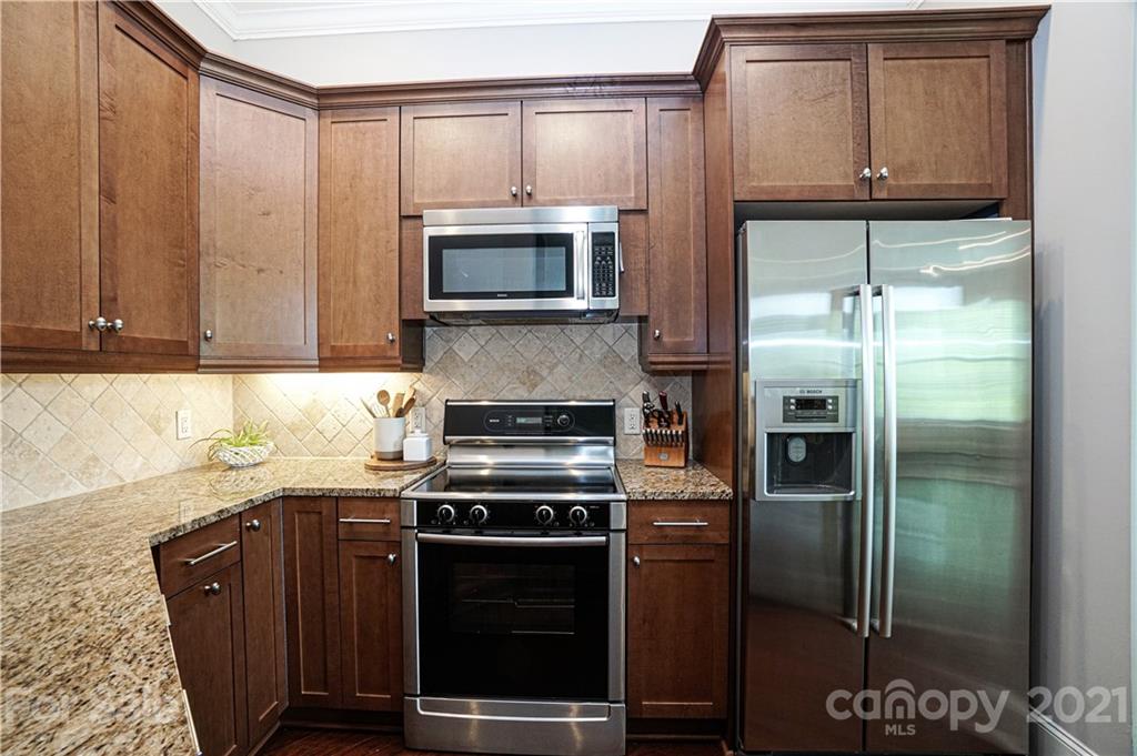 5425 Closeburn Road, Unit 103 Charlotte, NC 28210 - Photo 15 of 39 a kitchen with granite countertop a refrigerator and a stove top oven