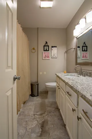 a bathroom with a granite countertop toilet sink and mirror