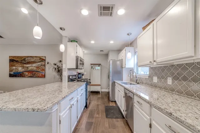 a large kitchen with stainless steel appliances granite countertop a lot of counter space and wooden floors