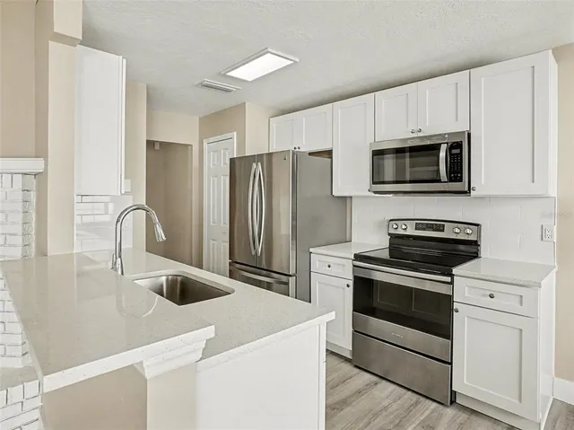 a kitchen with stainless steel appliances granite countertop a refrigerator and a sink