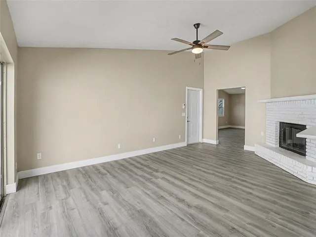 an empty room with wooden floor ceiling fan and windows