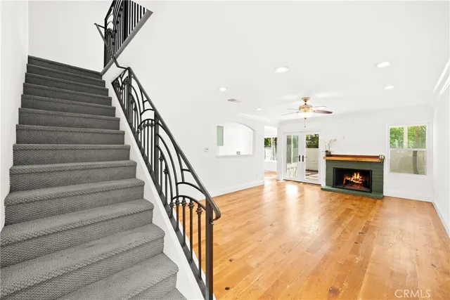 a view of a livingroom with a fireplace a ceiling fan and window